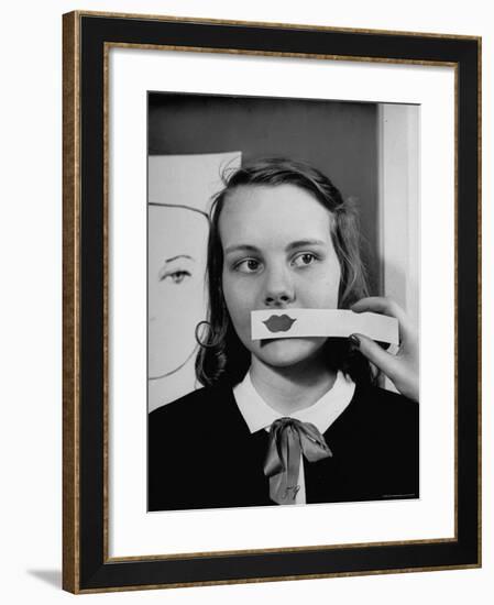 Young Girl Trying to Determine Which Lipstick Color Will Look Right with Her Complexion-Nina Leen-Framed Photographic Print