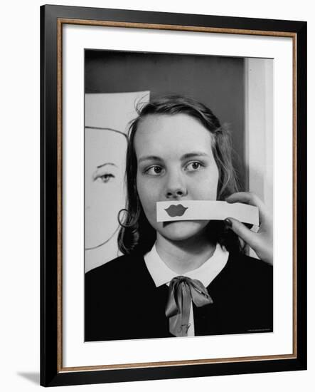 Young Girl Trying to Determine Which Lipstick Color Will Look Right with Her Complexion-Nina Leen-Framed Photographic Print