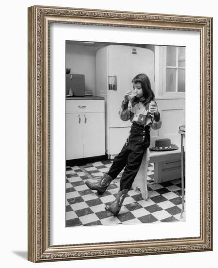 Young Girl Wearing Cowgirl Outfit Drinking Milk and Eating Sandwich in Kitchen-Nina Leen-Framed Photographic Print