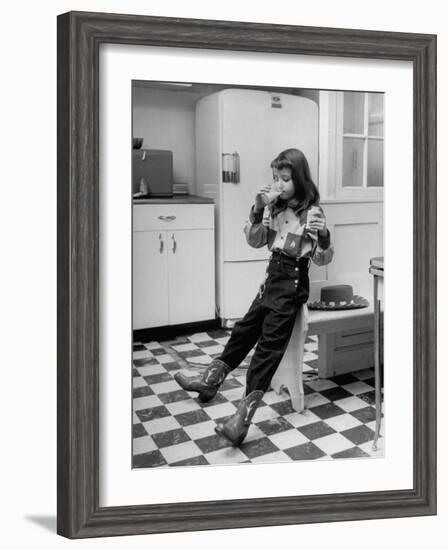 Young Girl Wearing Cowgirl Outfit Drinking Milk and Eating Sandwich in Kitchen-Nina Leen-Framed Photographic Print