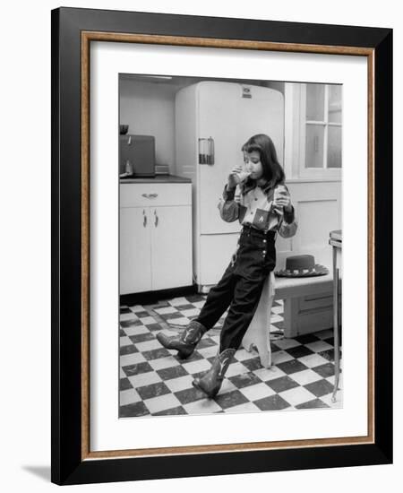 Young Girl Wearing Cowgirl Outfit Drinking Milk and Eating Sandwich in Kitchen-Nina Leen-Framed Photographic Print