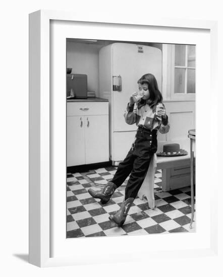 Young Girl Wearing Cowgirl Outfit Drinking Milk and Eating Sandwich in Kitchen-Nina Leen-Framed Photographic Print