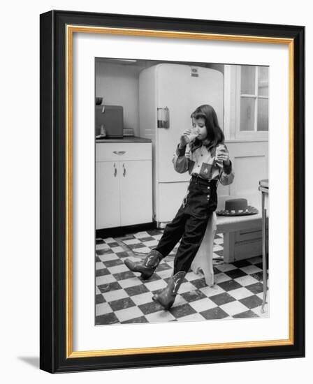 Young Girl Wearing Cowgirl Outfit Drinking Milk and Eating Sandwich in Kitchen-Nina Leen-Framed Photographic Print
