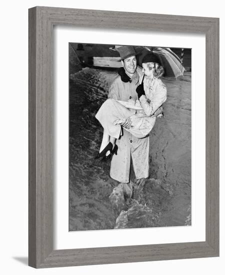 Young Man Carrying a Woman Through a Rainstorm-null-Framed Photo