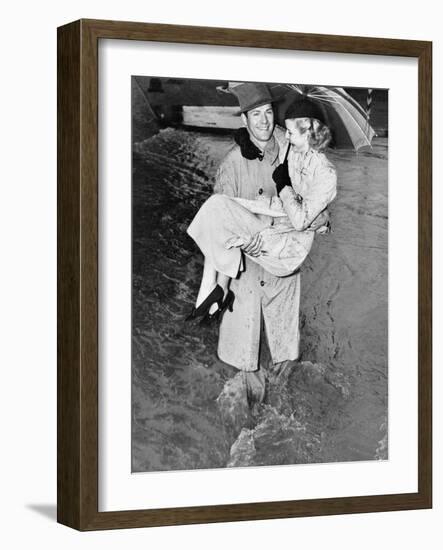 Young Man Carrying a Woman Through a Rainstorm-null-Framed Photo
