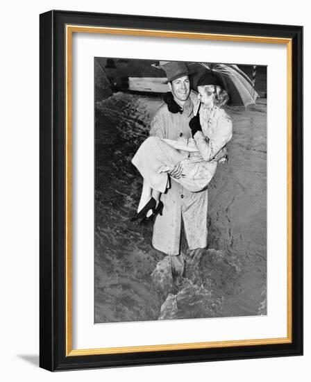 Young Man Carrying a Woman Through a Rainstorm-null-Framed Photo