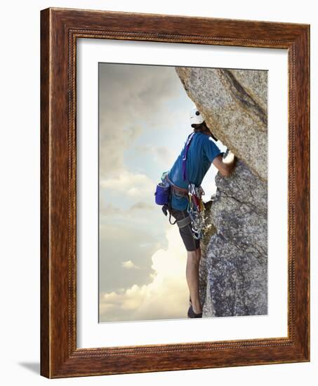 Young man rock climbing up a vertical cliff-null-Framed Photographic Print