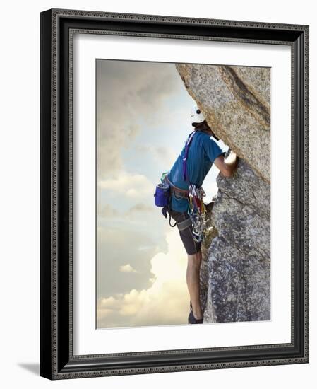 Young man rock climbing up a vertical cliff-null-Framed Photographic Print