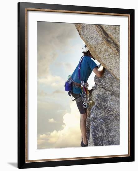 Young man rock climbing up a vertical cliff-null-Framed Photographic Print