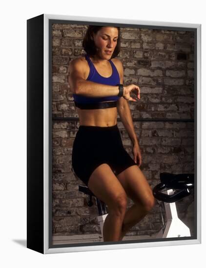 Young Woman Exercising on a Stationary Bike Checking her Heart Rate-null-Framed Premier Image Canvas