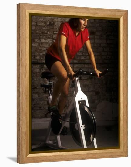 Young Woman Exercising on a Stationary Bike-null-Framed Premier Image Canvas