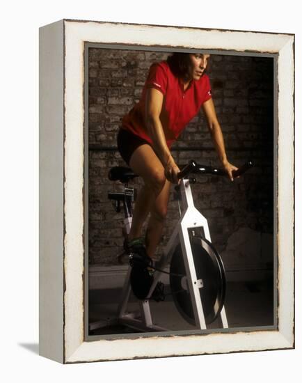 Young Woman Exercising on a Stationary Bike-null-Framed Premier Image Canvas