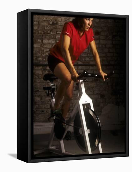 Young Woman Exercising on a Stationary Bike-null-Framed Premier Image Canvas