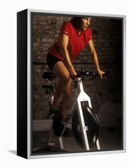 Young Woman Exercising on a Stationary Bike-null-Framed Premier Image Canvas
