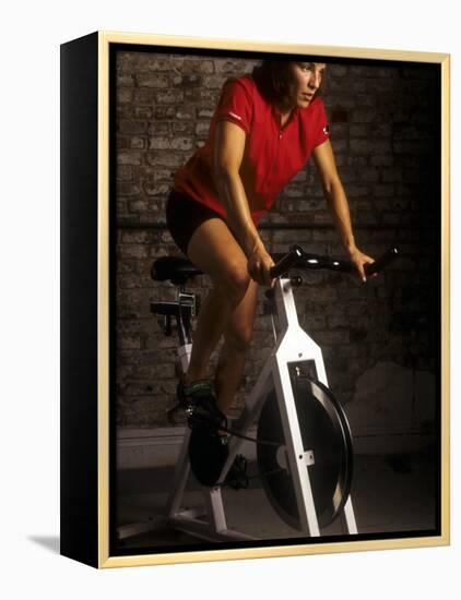 Young Woman Exercising on a Stationary Bike-null-Framed Premier Image Canvas