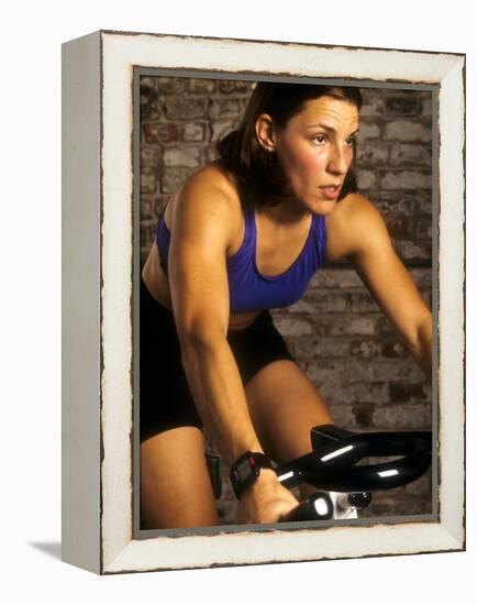 Young Woman Exercising on a Stationary Bike-null-Framed Premier Image Canvas