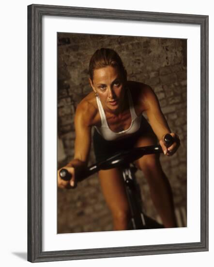 Young Woman Exercising on a Stationary Bike-null-Framed Photographic Print