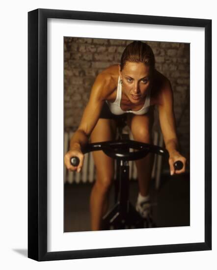 Young Woman Exercising on a Stationary Bike-null-Framed Photographic Print