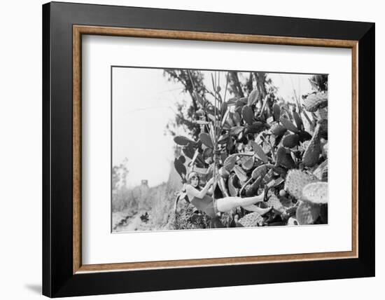 Young Woman Hanging from a Rope Next to Big Cactus Plants-null-Framed Photo