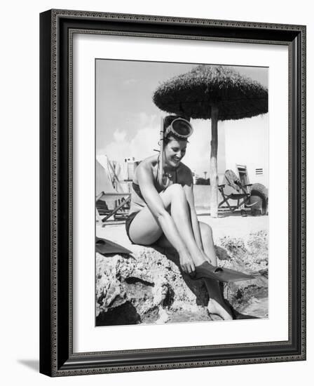 Young Woman in a Bikini Prepares to Go Snorkelling by Putting on Her Rubber Flippers-null-Framed Photographic Print