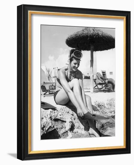 Young Woman in a Bikini Prepares to Go Snorkelling by Putting on Her Rubber Flippers-null-Framed Photographic Print