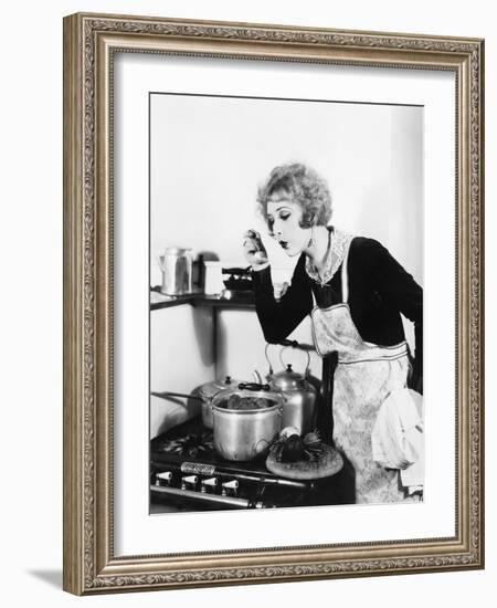 Young Woman in an Apron in Her Kitchen Tasting Her Food from a Pot-null-Framed Photo