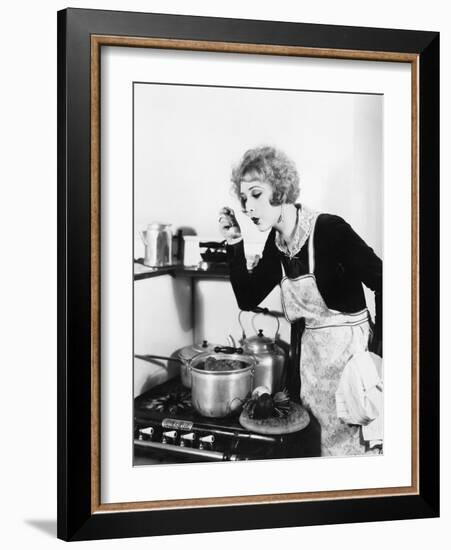 Young Woman in an Apron in Her Kitchen Tasting Her Food from a Pot-null-Framed Photo