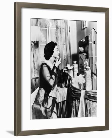 Young Woman Looking into a Mirror and Putting on Make Up-null-Framed Photo