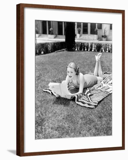 Young Woman Lying on a Towel in Her Yard Sunbathing and Reading-null-Framed Photo
