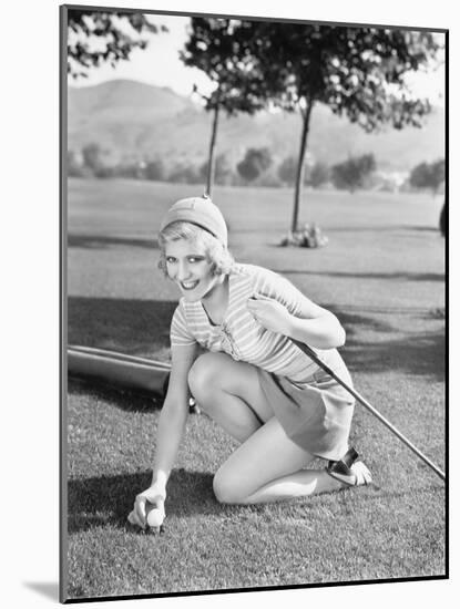 Young Woman on a Golf Course Placing a Golf Ball-null-Mounted Photo
