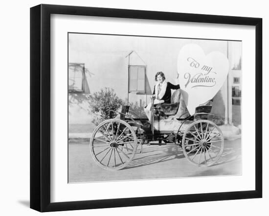 Young Woman Sitting on a Car Holding a Big Heart Shaped Sign-null-Framed Photo