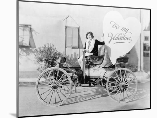 Young Woman Sitting on a Car Holding a Big Heart Shaped Sign-null-Mounted Photo