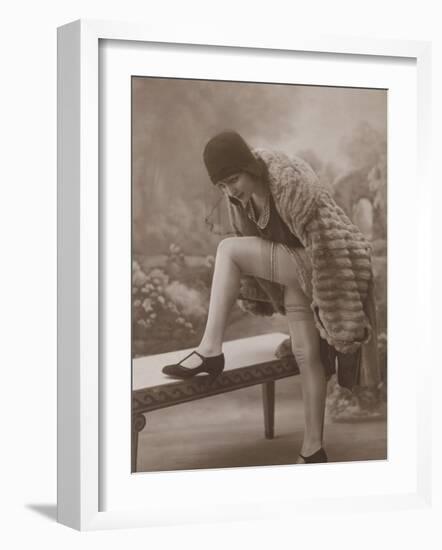Young Woman Wearing a Fur Coat Cloche Hat and T-Bar Shoes Lifts Her Leg Up-null-Framed Photographic Print