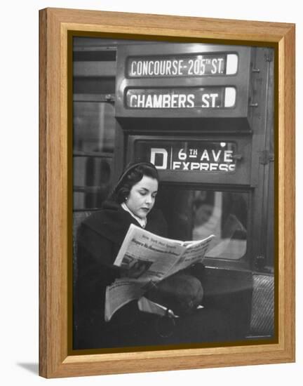 Young Woman Wearing a Winter Coat and Hat, Reading Beneath "D 6th Avenue" Sign, Riding the Subway-Eliot Elisofon-Framed Premier Image Canvas