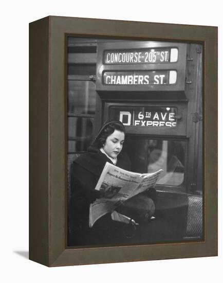 Young Woman Wearing a Winter Coat and Hat, Reading Beneath "D 6th Avenue" Sign, Riding the Subway-Eliot Elisofon-Framed Premier Image Canvas