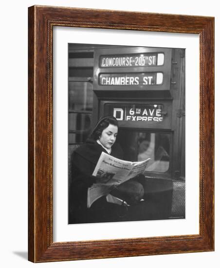 Young Woman Wearing a Winter Coat and Hat, Reading Beneath "D 6th Avenue" Sign, Riding the Subway-Eliot Elisofon-Framed Photographic Print