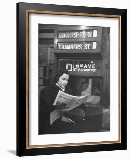 Young Woman Wearing a Winter Coat and Hat, Reading Beneath "D 6th Avenue" Sign, Riding the Subway-Eliot Elisofon-Framed Photographic Print