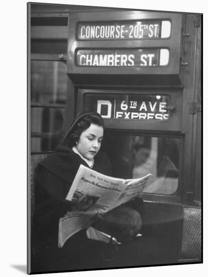 Young Woman Wearing a Winter Coat and Hat, Reading Beneath "D 6th Avenue" Sign, Riding the Subway-Eliot Elisofon-Mounted Photographic Print