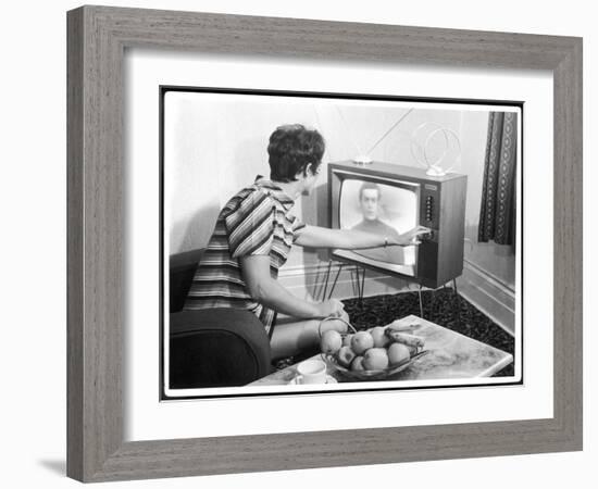 Young Woman with Short Dark Hair Wearing a Stripy Mini Dress Adjusts Her Television Set-null-Framed Art Print