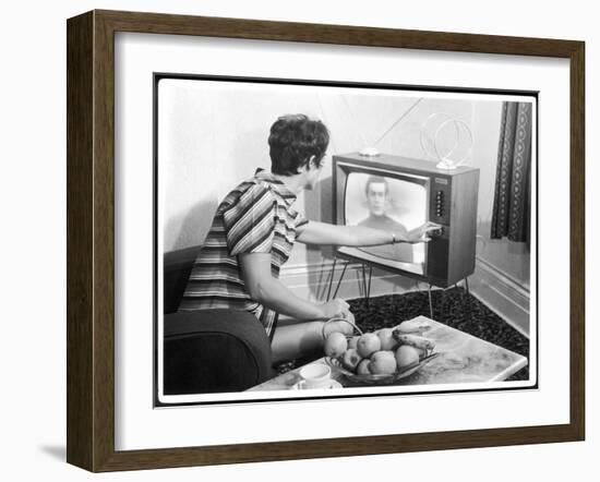 Young Woman with Short Dark Hair Wearing a Stripy Mini Dress Adjusts Her Television Set-null-Framed Art Print