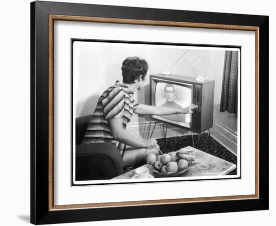 Young Woman with Short Dark Hair Wearing a Stripy Mini Dress Adjusts Her Television Set-null-Framed Art Print