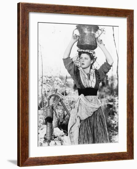 Young Woman with Water Bucket on Her Head Next to a Well-null-Framed Photo