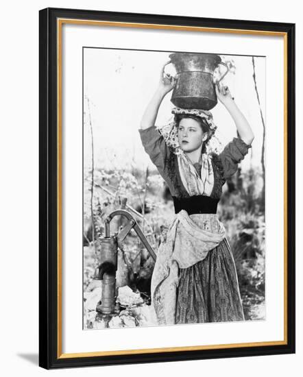 Young Woman with Water Bucket on Her Head Next to a Well-null-Framed Photo